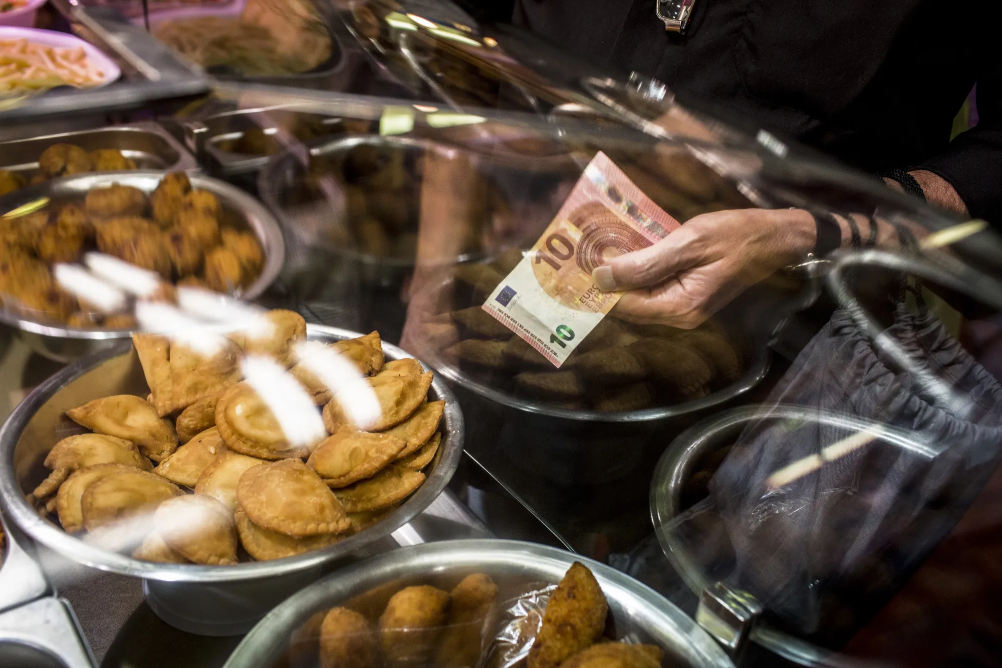 A customer holds a ten euro banknote to purchase pastries in the Sant Antoni market in Barcelona.