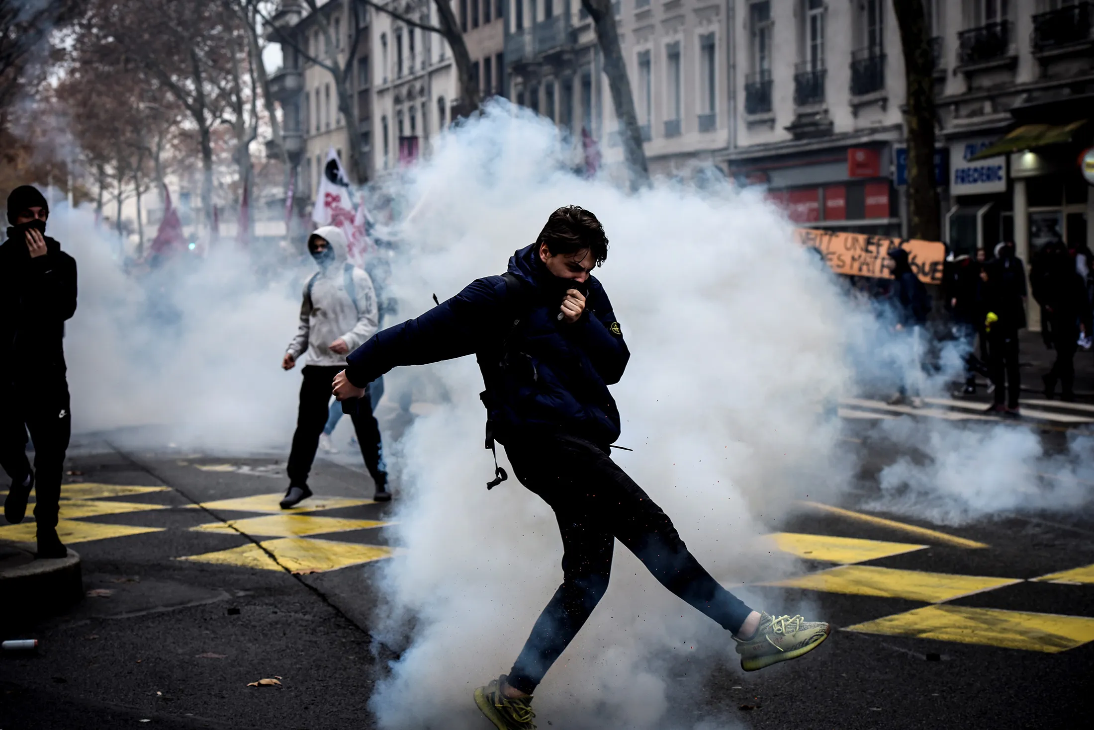 A demonstrator kicks a smoke grenade shot by riot police during a demonstration by high school students in Lyon, on Dec.&nbsp;7.