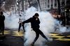 A demonstrator kicks a smoke grenade shot by riot police during a demonstration by high school students in Lyon, on Dec. 7.
