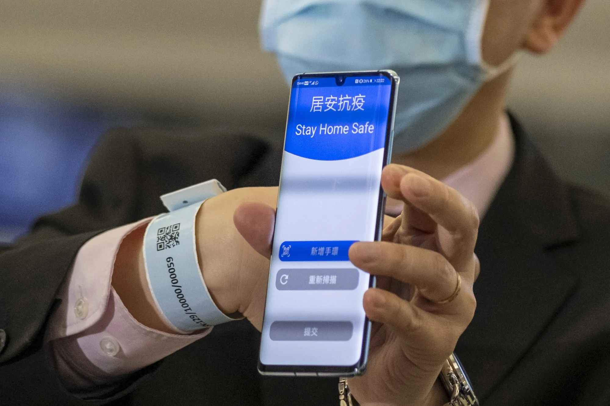 An official shows a bracelet and complementary tracking app that will be given to inbound travelers requiring compulsory home-quarantine during a news conference at Hong Kong International Airport&nbsp;on March 18.