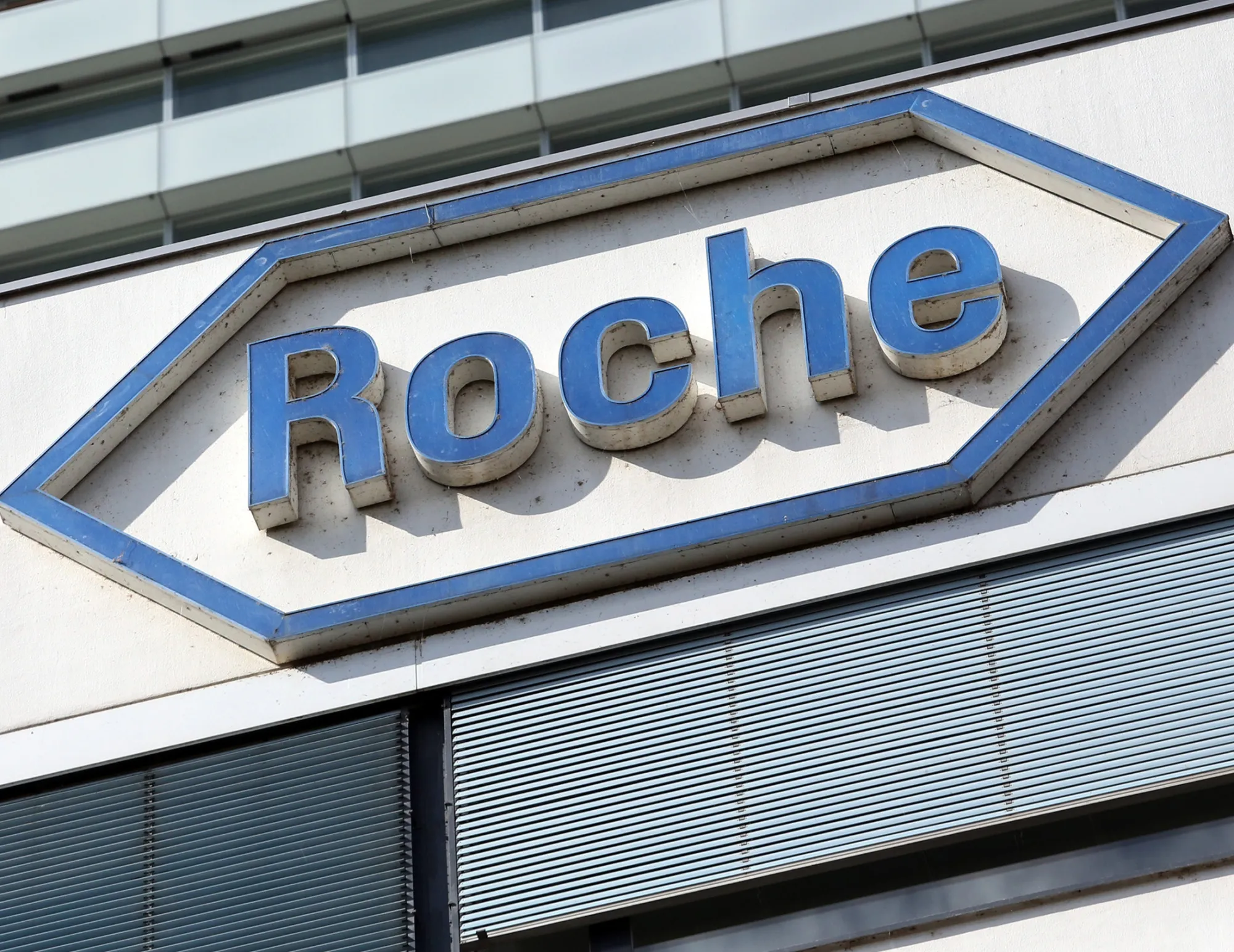 A sign stands outside the entrance of the Roche Holding AG headquarters in in Basel, Switzerland, on Tuesday, Sept. 8, 2015. Roche Holding AG Chief Executive Officer Severin Schwan blasted a U.K. decision to stop funding some cancer drugs, calling the choice 'stupid'.
