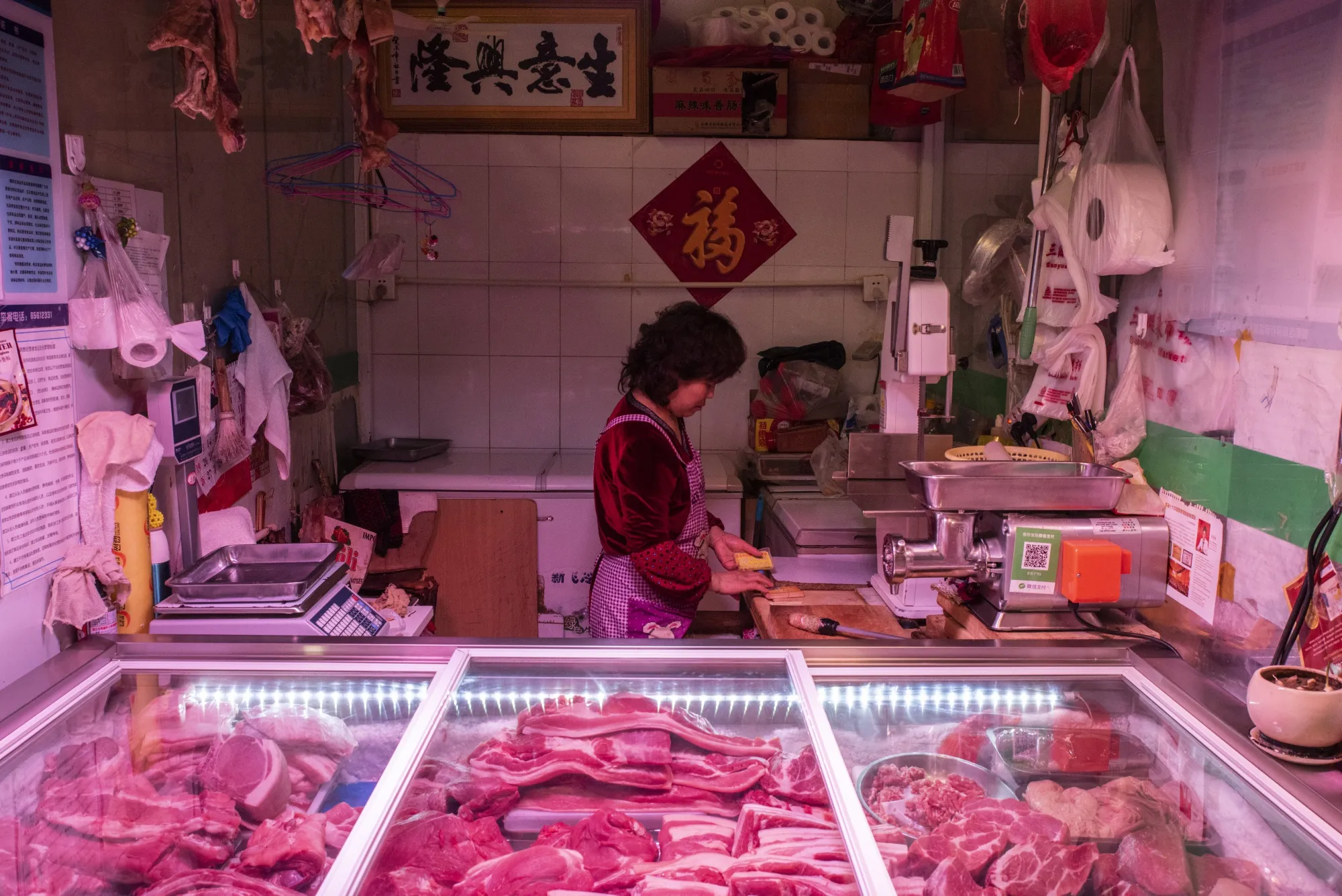 A pork vendor stands behind the counter at a market stall in Beijing.