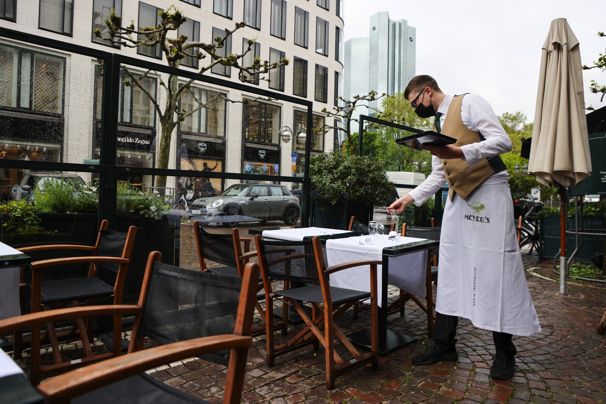 A waiter sets up restaurant terrace tables&nbsp;in Frankfurt, Germany.