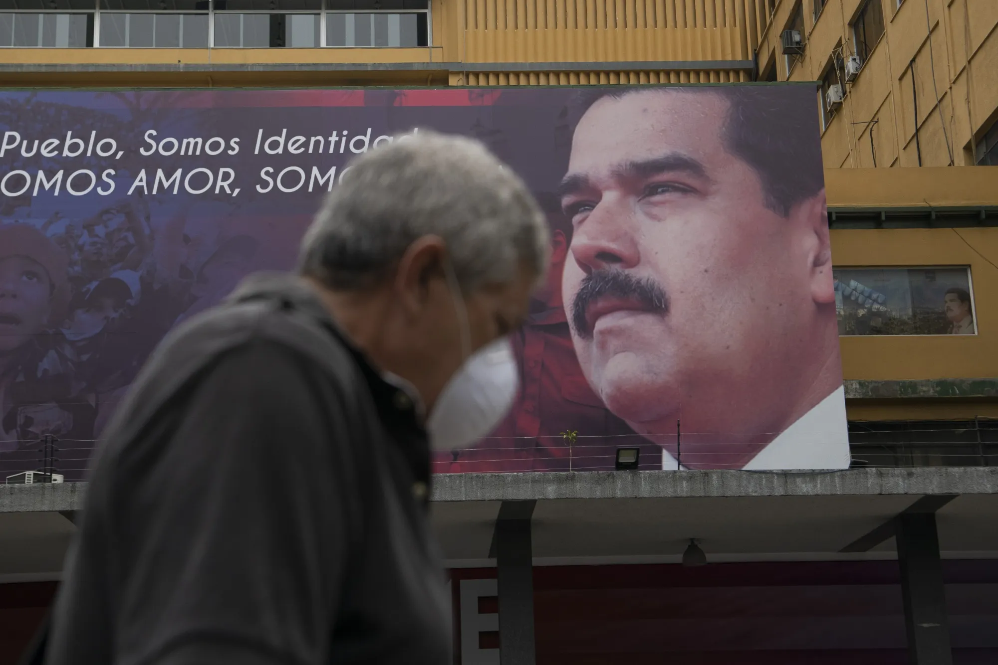 A pedestrian passes by a billboard featuring an image of Nicolas Maduro in Caracas.