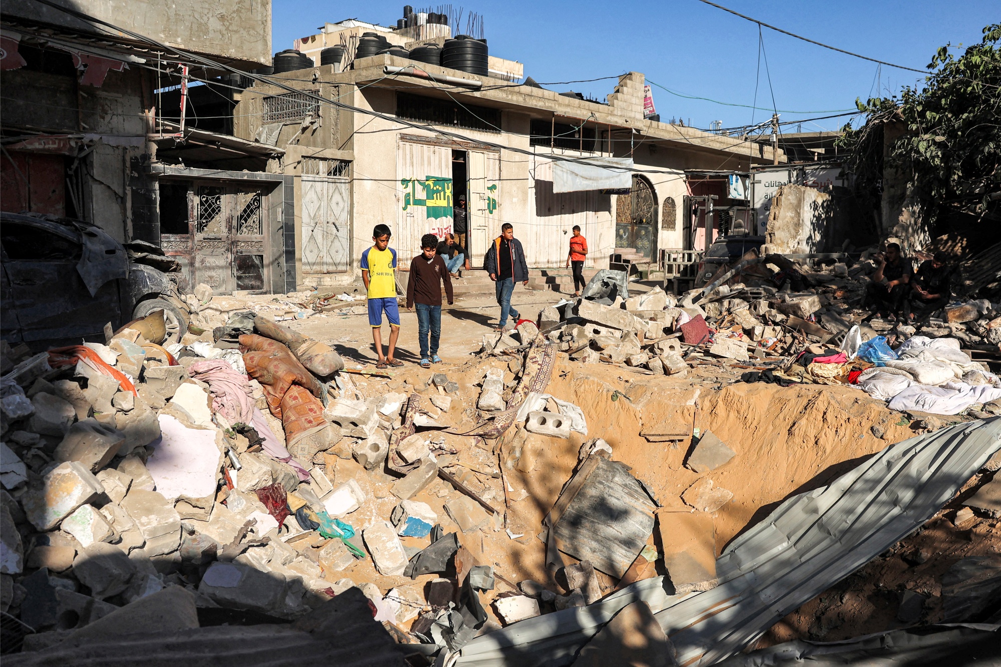 Children stand by a crater at the site of a building following Israeli bombardment in Rafah,&nbsp;on May 8.