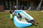 Jalen Askari, 7, right, plugs his nose as he falls into the pool he is playing in with his siblings, from left, Amari, 5, Bella, 2, and DJ, 10, in Portland, Ore., Tuesday, July 26, 2022. Temperatures are expected to top 100 degrees F (37.8 C) on Tuesday and wide swaths of western Oregon and Washington are predicted to be well above historic averages throughout the week. (AP Photo/Craig Mitchelldyer)