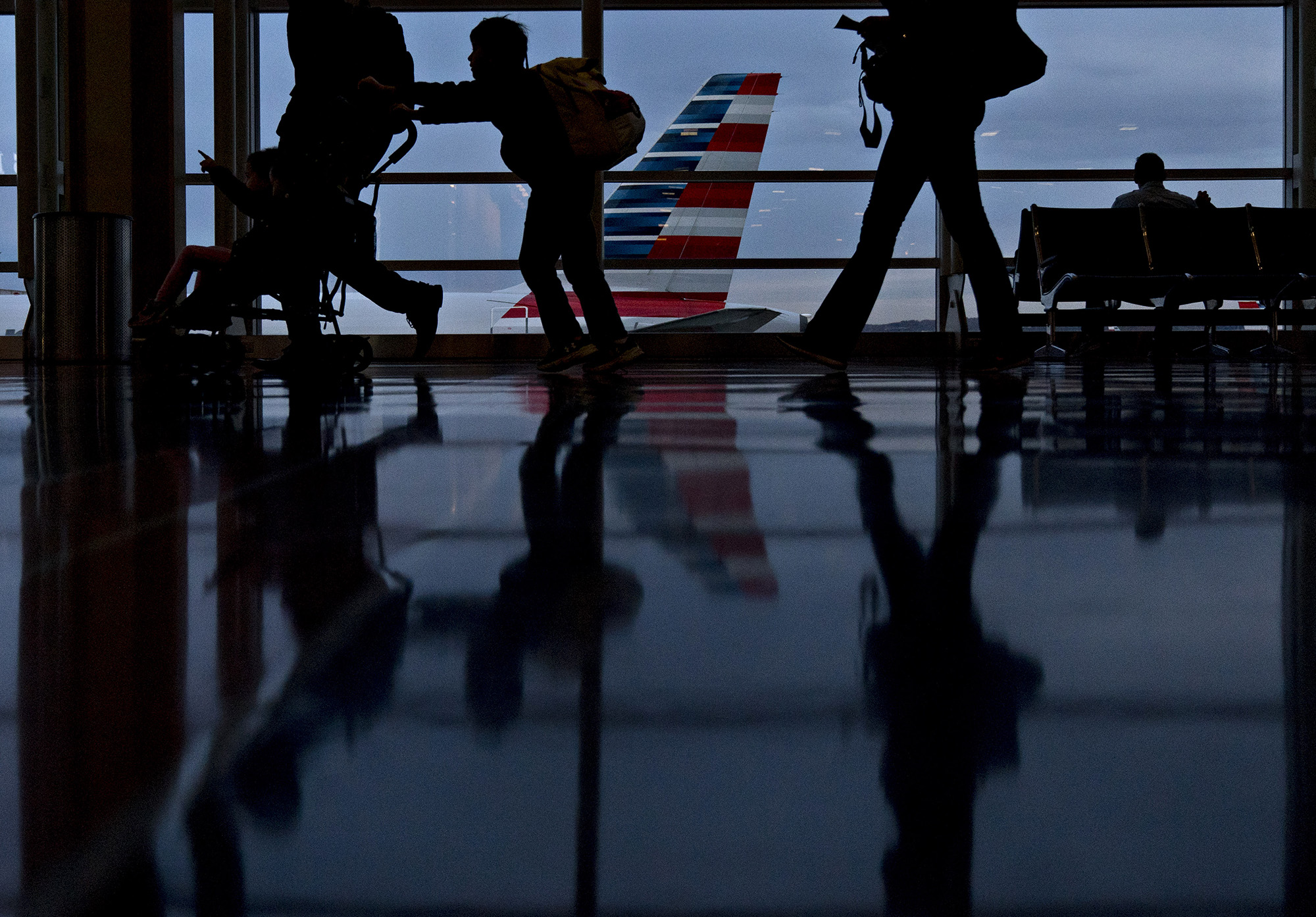Travelers walk past an American Airlines Group Inc. aircraft at Ronald Reagan National Airport (DCA) in Washington, D.C.
