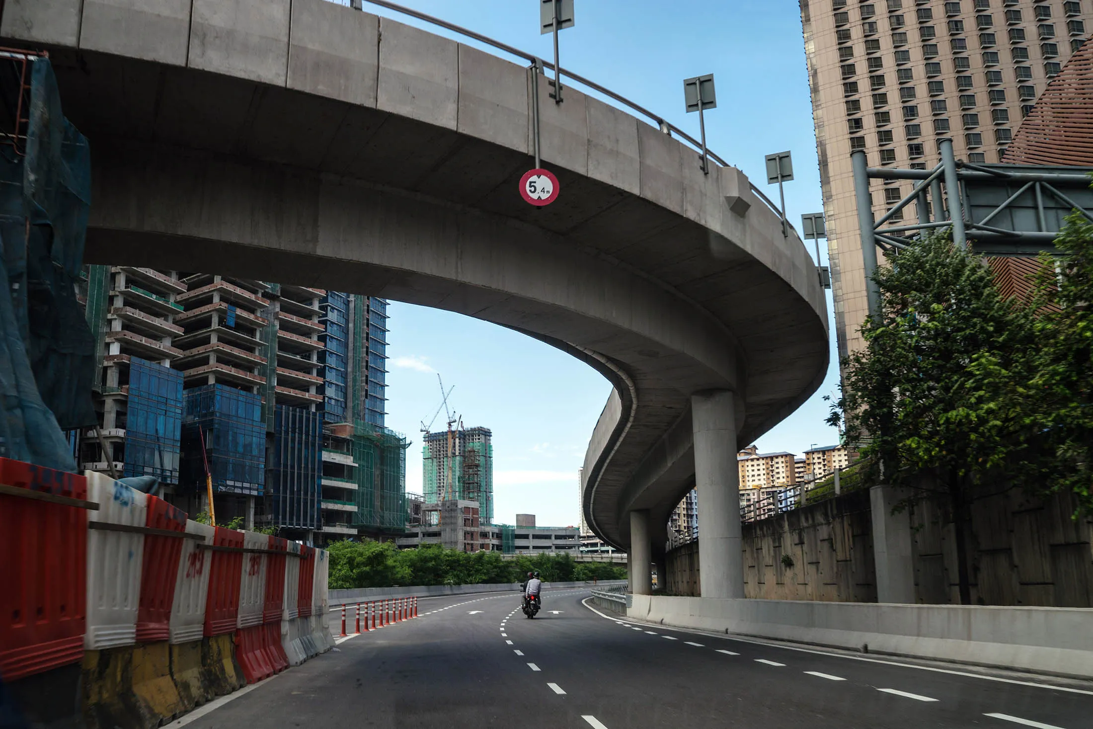 A motorcyclist travels under a monorail bridge near a construction site in the Mid Valley area of Kuala Lumpur, Malaysia.
