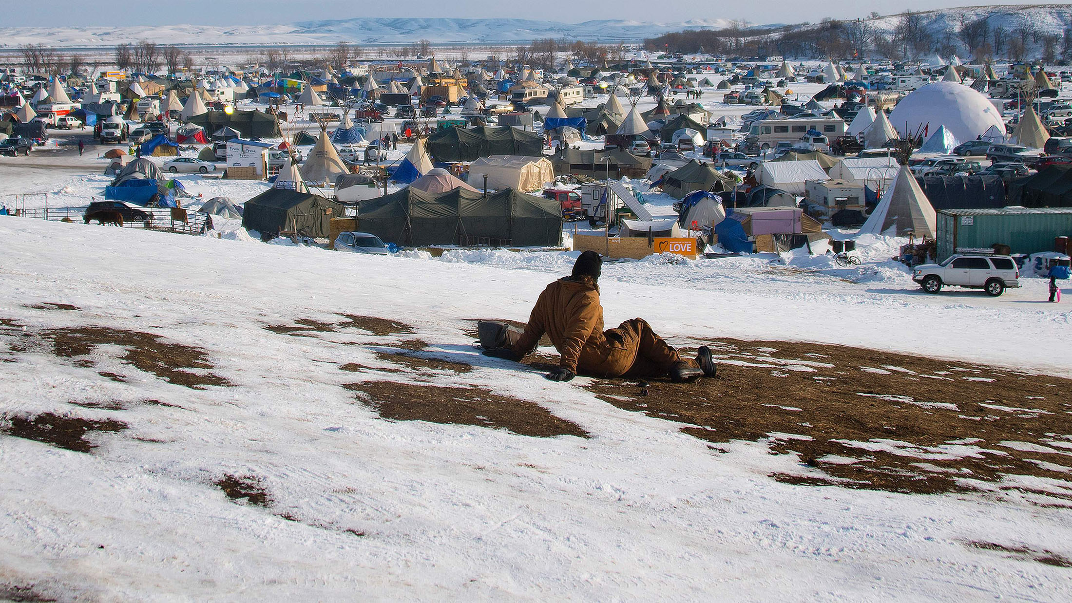 A man looks out over the Oceti Sakowin Camp on the edge of the Standing Rock Sioux Reservation on December 3, 2016 outside Cannon Ball, North Dakota, as Native Americans and activists from around the country gather at the camp trying to halt the construction of the Dakota Access Pipeline. / AFP / JIM WATSON (Photo credit should read JIM WATSON/AFP/Getty Images)
