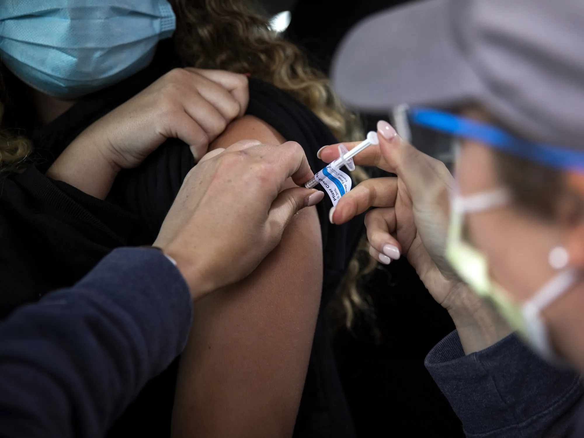 A healthcare worker administers a&nbsp;Covid-19 vaccine to a teenager at a mass vaccination site at Portland International Airport.