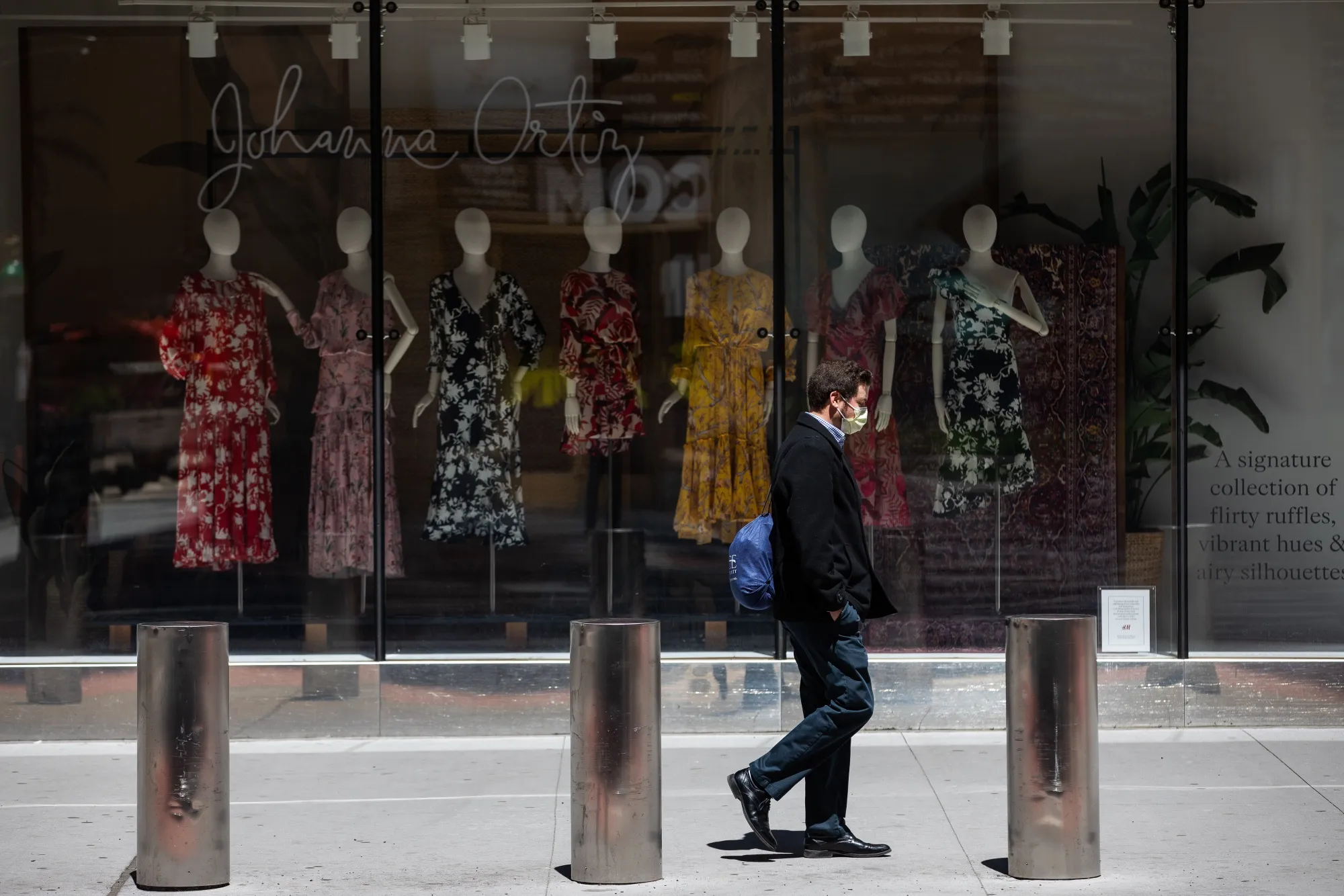 A pedestrian wearing a protective mask passes in front of an H&amp;M&nbsp;store temporarily closed in the Times Square area of New York on May 12.