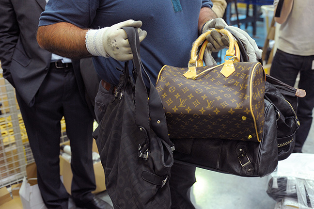 A customs officer shows seized counterfeit handbags. Photographer: Eric Piermont/AFP via Getty Images
