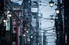 Power and utility cables hang from poles on a street in Hachioji in Tokyo.