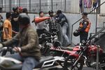 An armed group attacks a person as a Bolivarian National Police (PNB) officer stands by.