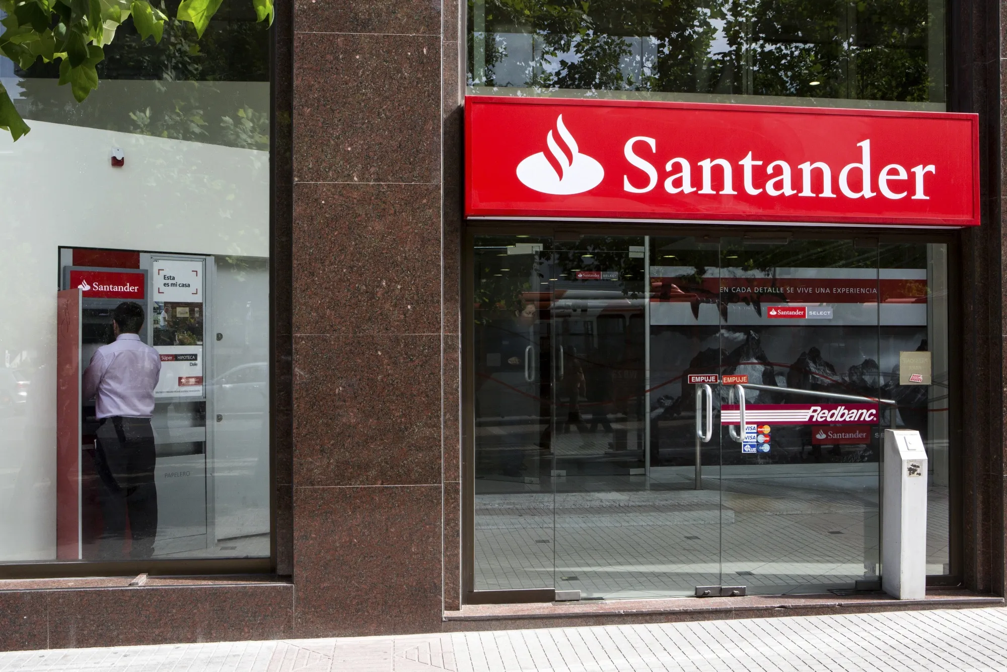 A person uses an ATM at a Banco Santander SA branch in Santiago, Chile.