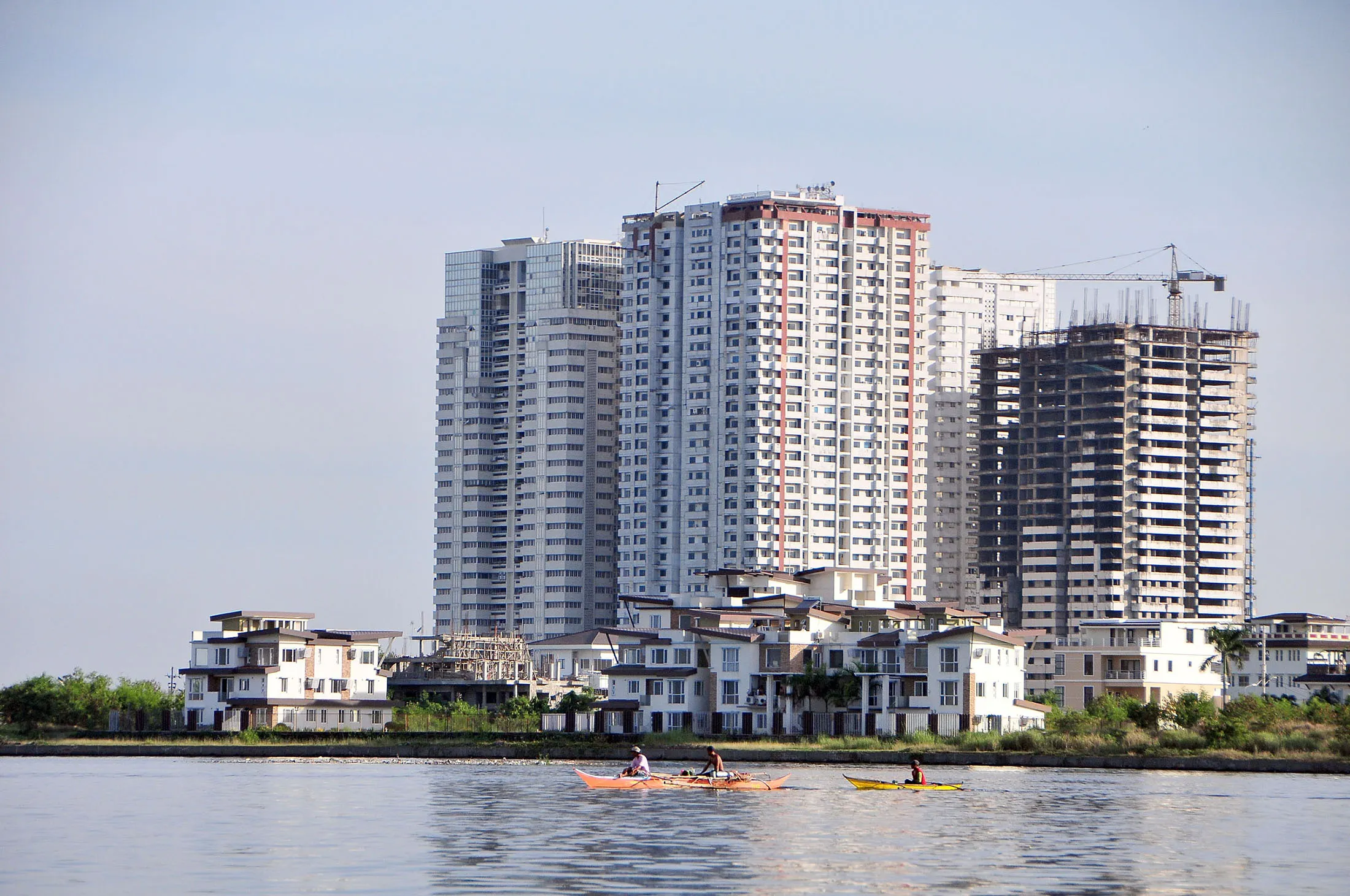 Local fishermen paddle past residential condominiums and townhouses in Manila.