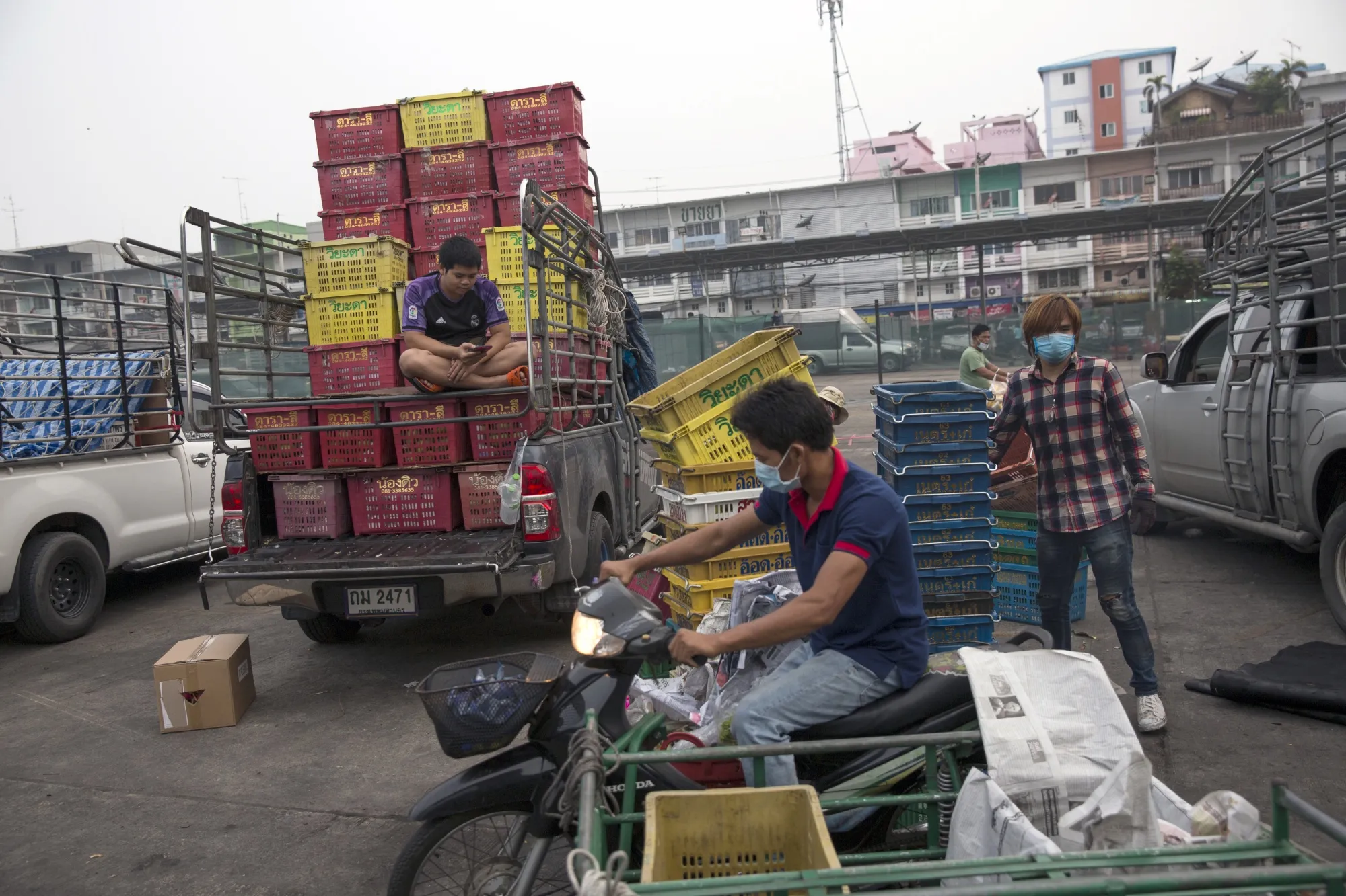 A motorcyclist wearing a protective mask rides past workers at the Talat Thai wholesale market in Rangsit, Pathum Thani, Thailand.
