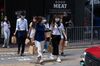 Pedestrians wearing protective masks walk with their takeout meals during lunch hour in Tsim Sha Tsui district in Hong Kong, China.