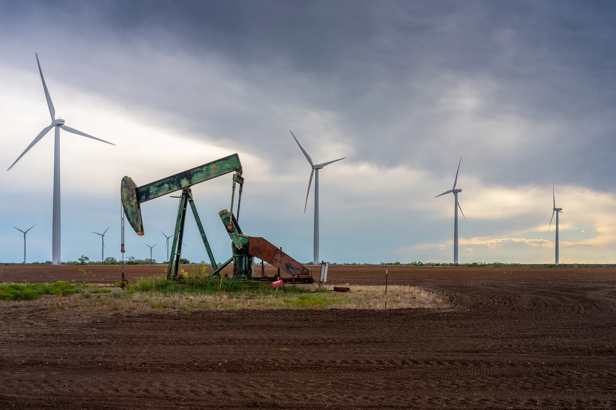 An oil pumpjack near a field of wind turbines in Nolan, Texas.