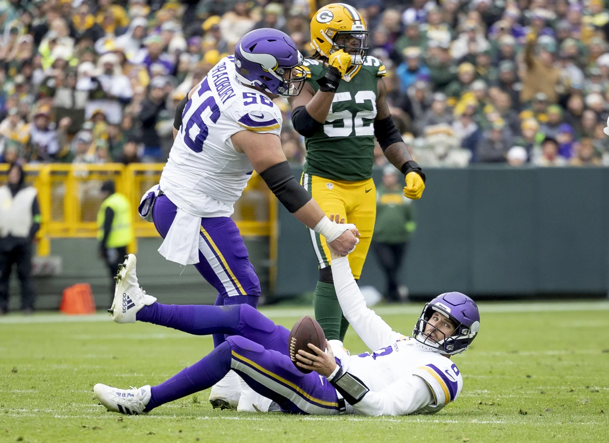 CORRECTS BYLINE TO CARLOS GONZALEZ/STAR TRIBUNE - - Minnesota Vikings quarterback Kirk Cousins (8) is helped up by teammate Garrett Bradbury (56) after a sack in the fourth quarter of an NFL football game against the Green Bay Packers in Miami Gardens, Fla., Sunday, Oct. 29, 2023. (Carlos Gonzalez/Star Tribune via AP)