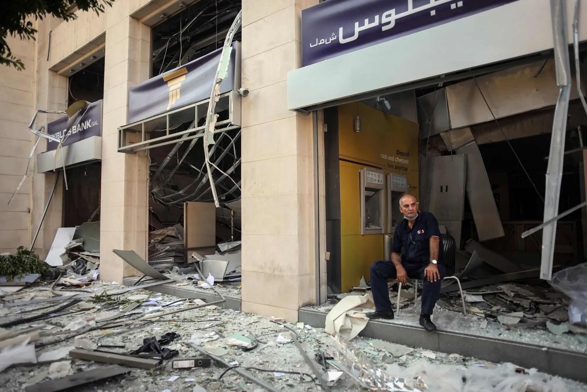 A private security guard sits at the entrance of a destroyed bank branch in Beirut on Aug. 5.
