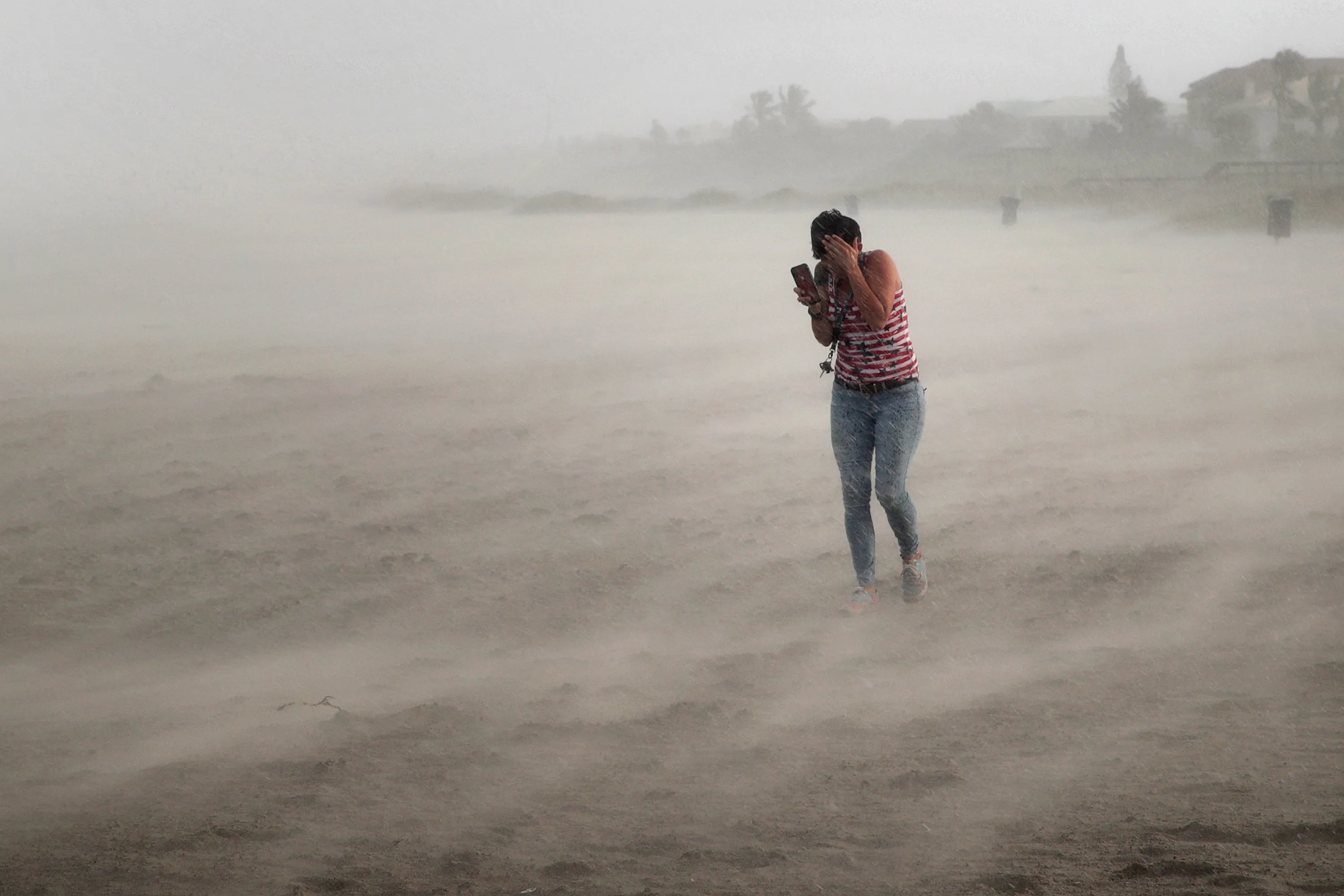 A woman seeks cover from blowing sand and rain whipped up by Hurricane Dorian in Cocoa Beach, Florida on Sept. 2.