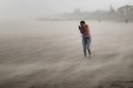 A woman seeks cover from blowing sand and rain whipped up by Hurricane Dorian in Cocoa Beach, Florida on Sept. 2.