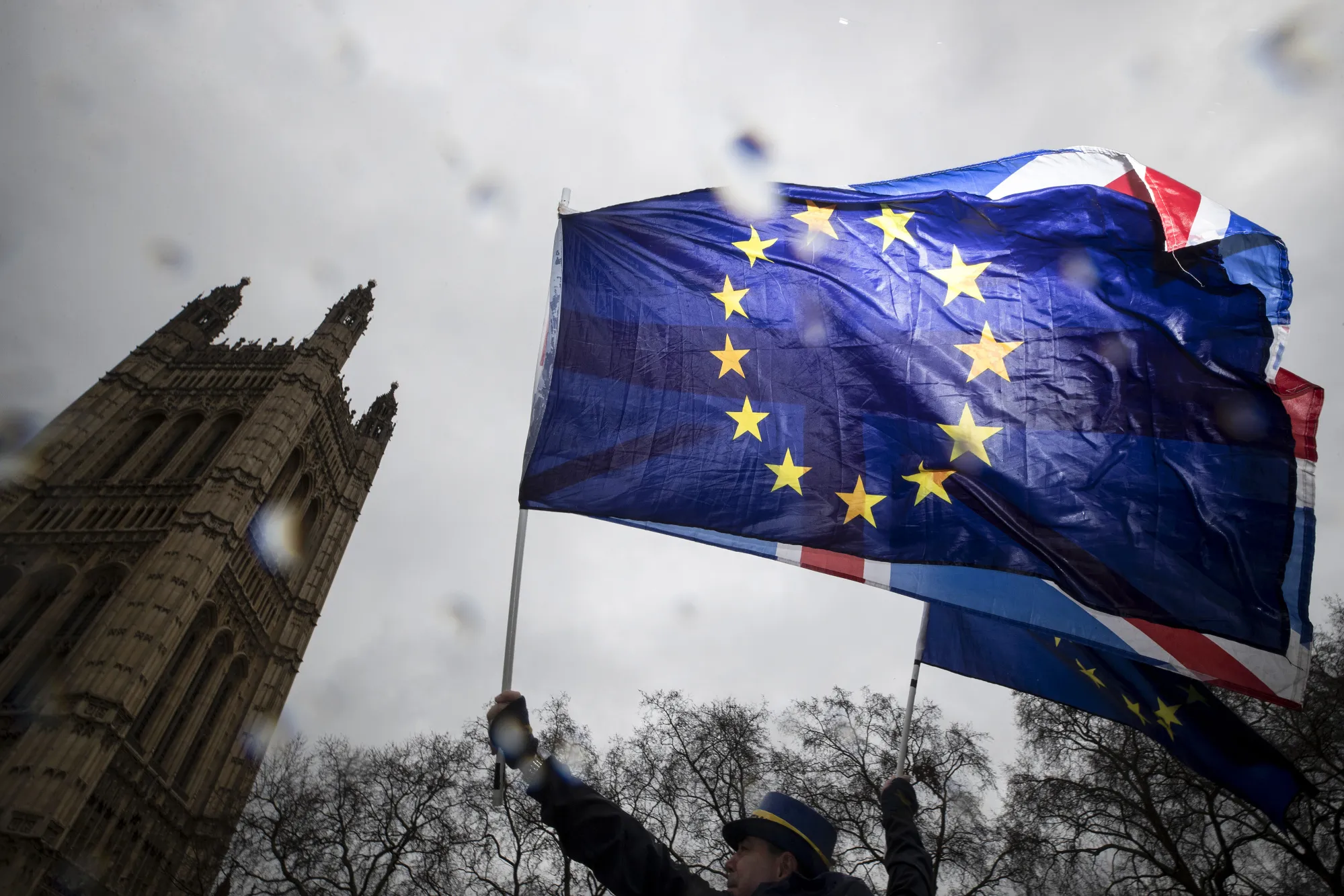 A demonstrator waves a European Union (EU) flag and a Union flag, also known as a Union Jack, during an anti-Brexit demonstration outside Parliament in London.