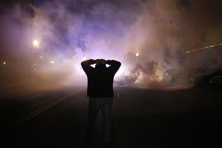 A protester puts his hands on his head as a cloud of tear gas approaches after a grand jury returned no indictment in the shooting of Michael Brown in Ferguson, Missouri, November 24, 2014.