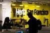 An employee wears a protective mask while assisting a customer at the Hertz Global Holdings Inc. rental counter at San Francisco International Airport in San Francisco, California, U.S., on Tuesday, May 5, 2020. Hertz Global Holdings said it entered into forbearances and limited waivers with certain of the Company's corporate lenders and holders of the company’s asset-backed vehicle debt.