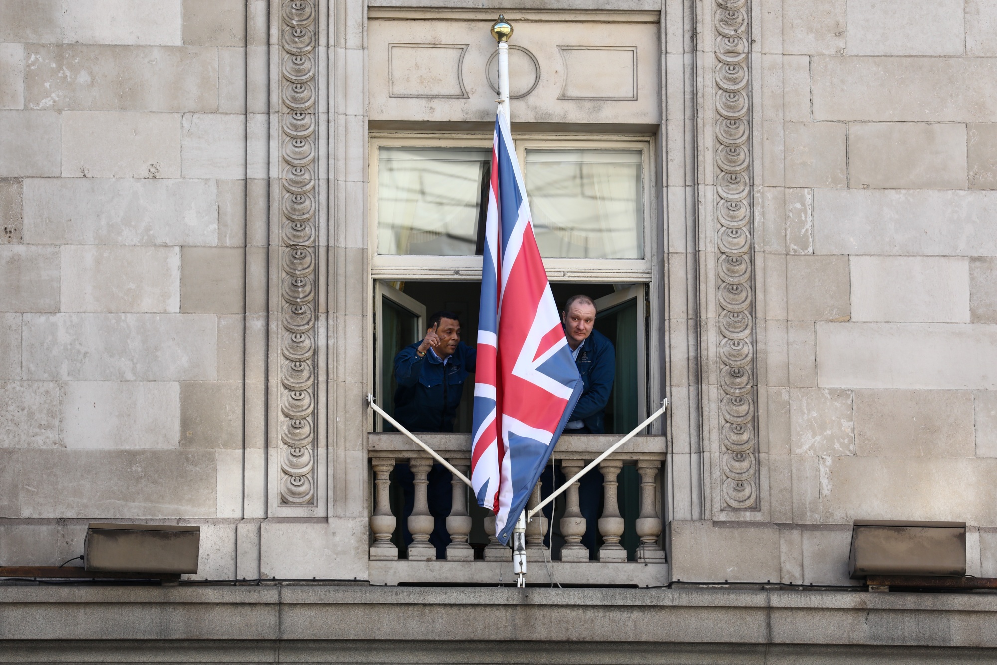 Workers at the shuttered The Ritz hotel bring in a British Union Flag, also known as Union Jack, in London.