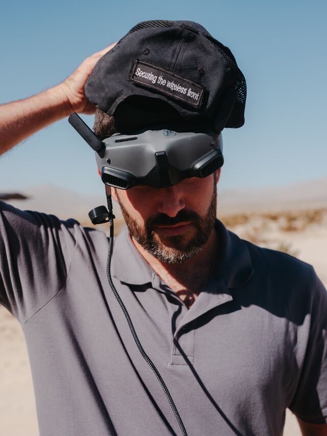 A member of the Israeli defense company R2 puts on a pair of FPV drone goggles at the National Training Center  in Fort Irwin.
