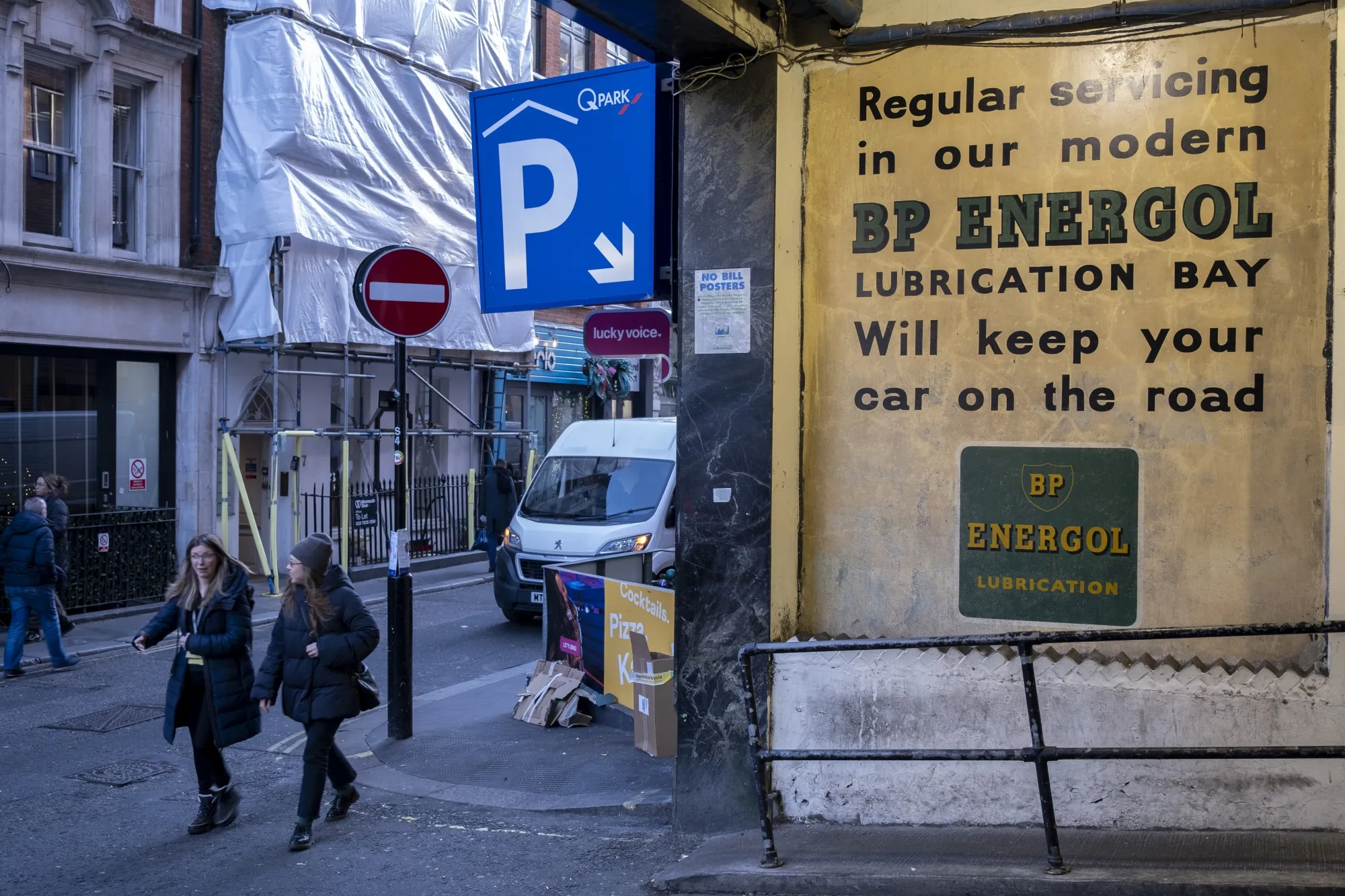 Old advertising posters for BP Energol at the entrance to a parking garage in Soho, London.