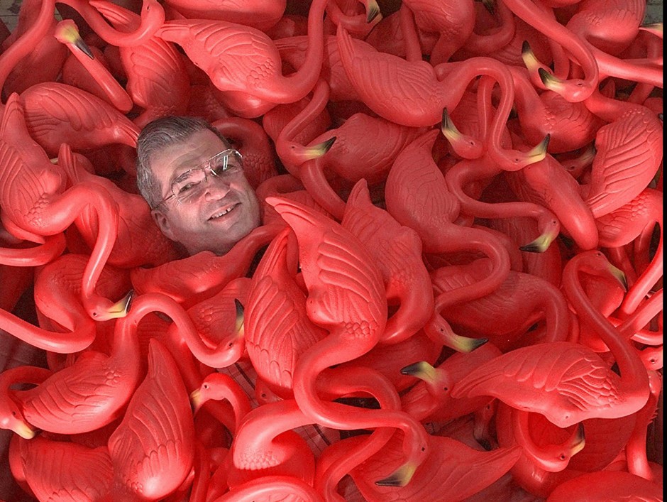 Don Featherstone, creator of the original plastic pink flamingo, lies surrounded by many of his plastic creatures. Featherstone died Monday at the age of 79.
