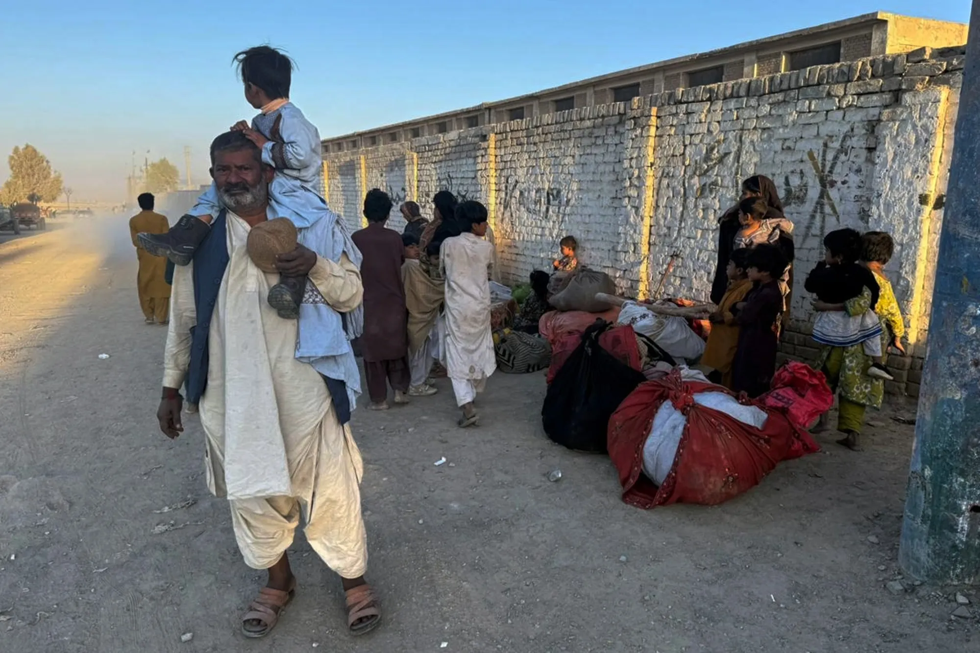 Residents who fled their homes following border clashes between Pakistan and Afghan forces wait for transportation in Chaman, Afghanistan, on Oct. 15.