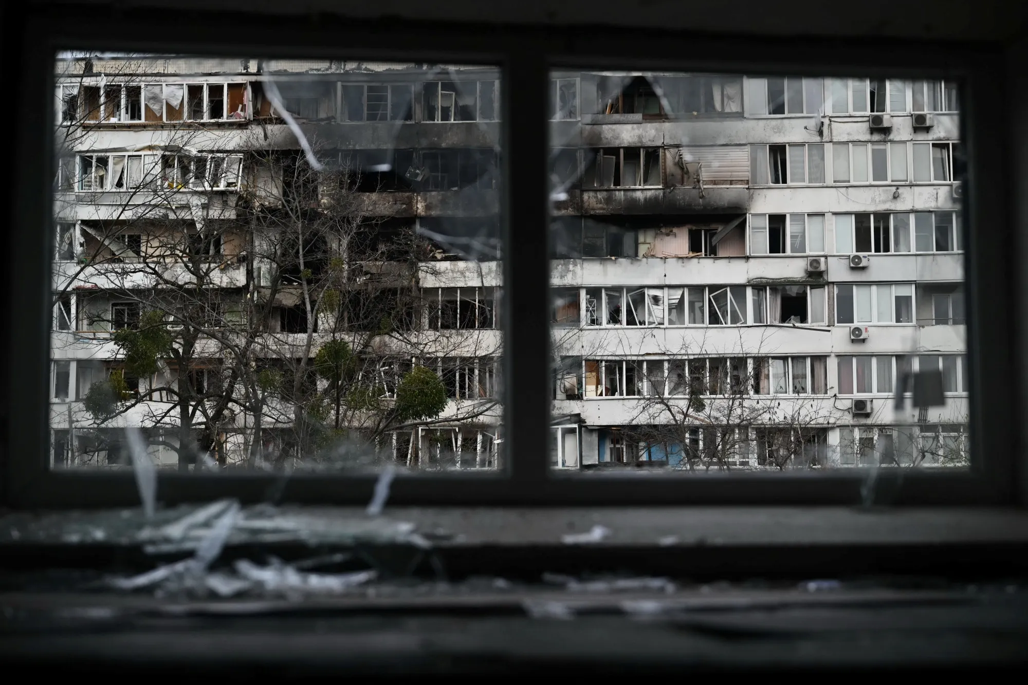 A damaged residential building as seen through a broken window on Nov. 25, following an air attack in Kyiv.&nbsp;