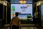 People walk past a screen displaying news featuring on Adani Group inside the BSE building in Mumbai, India, on Thursday, Feb. 2, 2023.