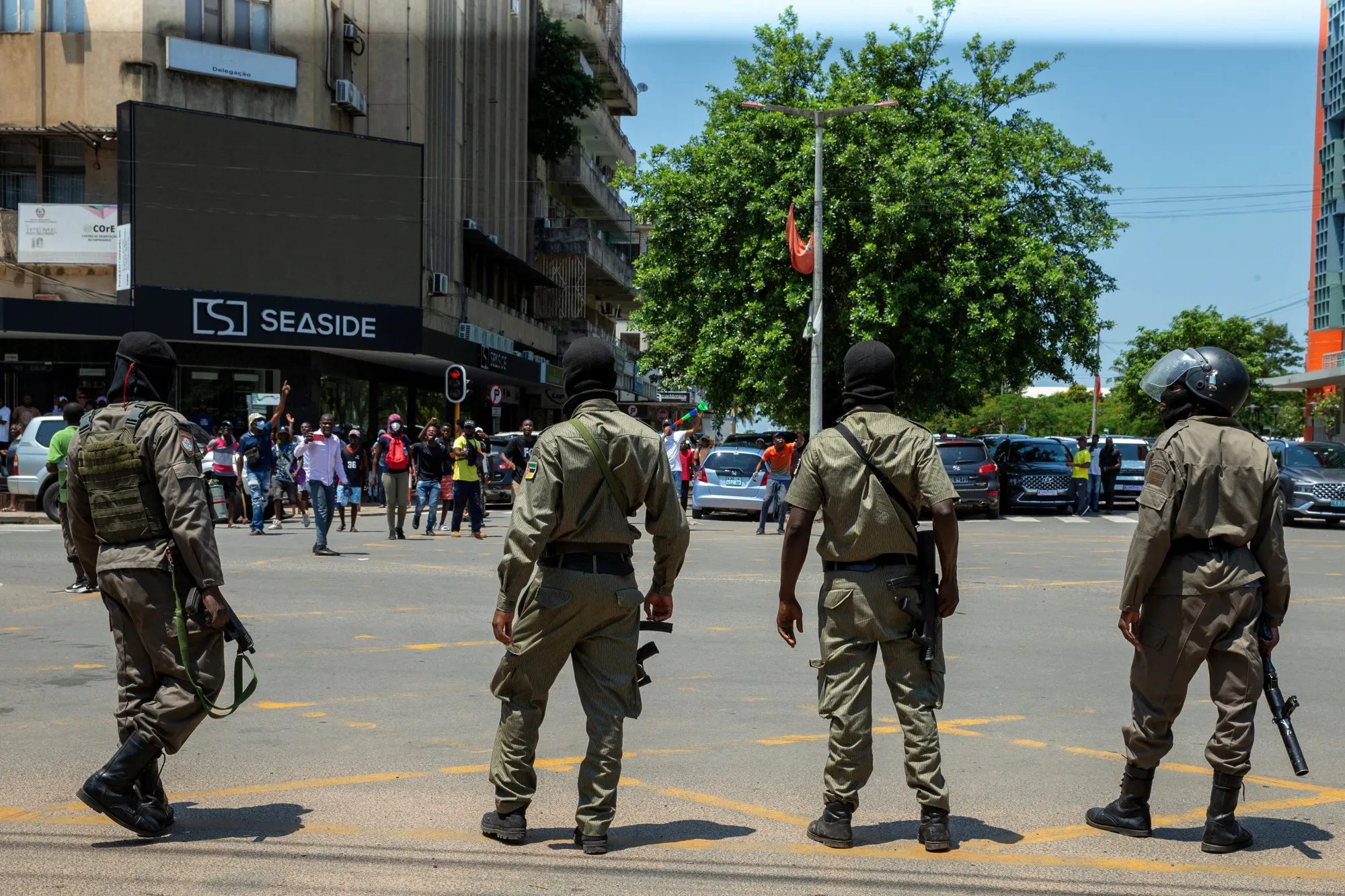Police officers look on as protesters gather in Maputo on Jan. 15.