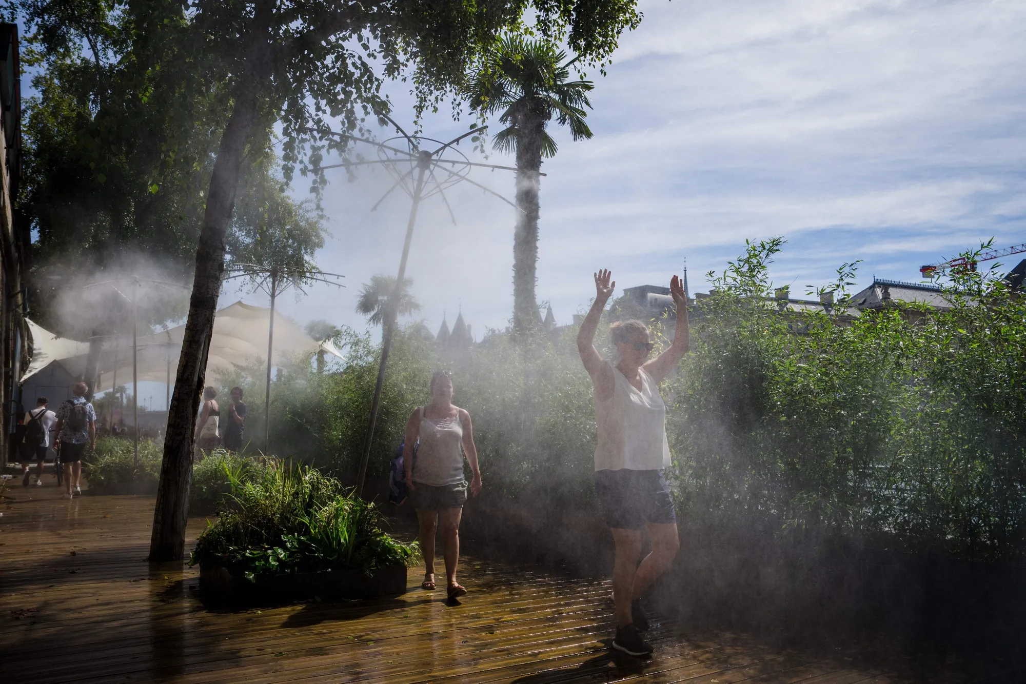 Women use a mist machine to cool down on the Seine embankment in Paris.