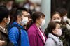 Pedestrians wearing protective masks wait to cross a road in the Ginza area in Tokyo, Japan.