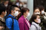 Pedestrians wearing protective masks wait to cross a road in the Ginza area in Tokyo, Japan.
