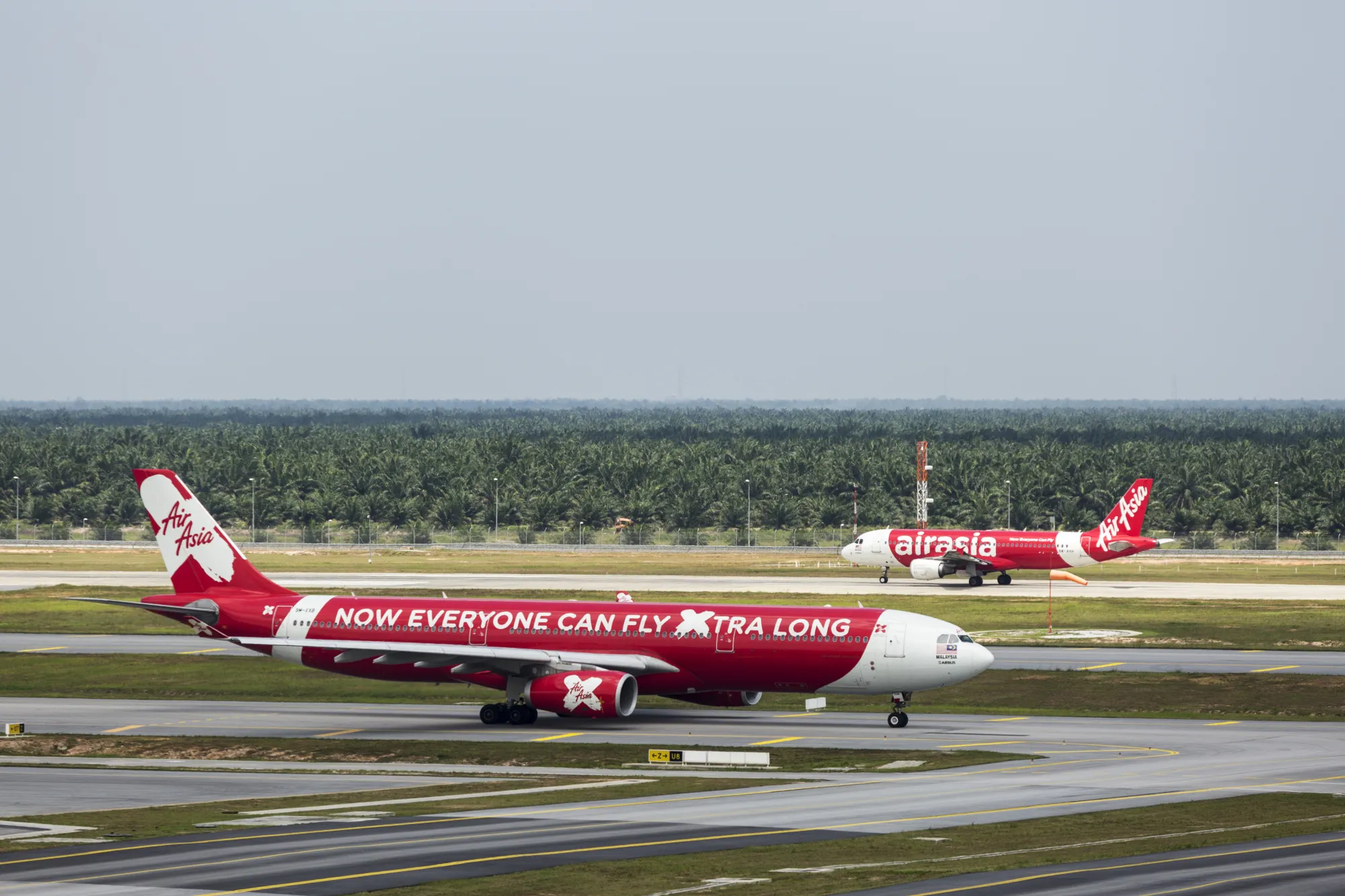 An AirAsia Bhd. aircraft, right, prepares to take off as an AirAsia X Bhd. aircraft taxis on the tarmac at Kuala Lumpur International Airport 2&nbsp;in Sepang, Selangor, Malaysia.