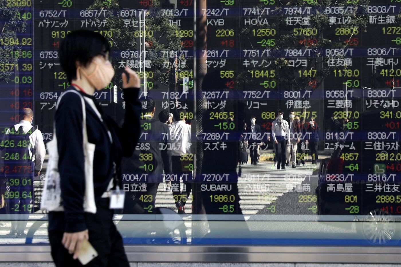 Pedestrians reflected in an electronic stock board outside a securities firm in Tokyo, Japan, on Thursday, Oct. 29, 2020.