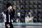 Pedestrians reflected in an electronic stock board outside a securities firm in Tokyo, Japan, on Thursday, Oct. 29, 2020.
