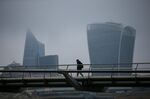 A pedestrian crosses the Millennium Bridge beyond the City of London.
