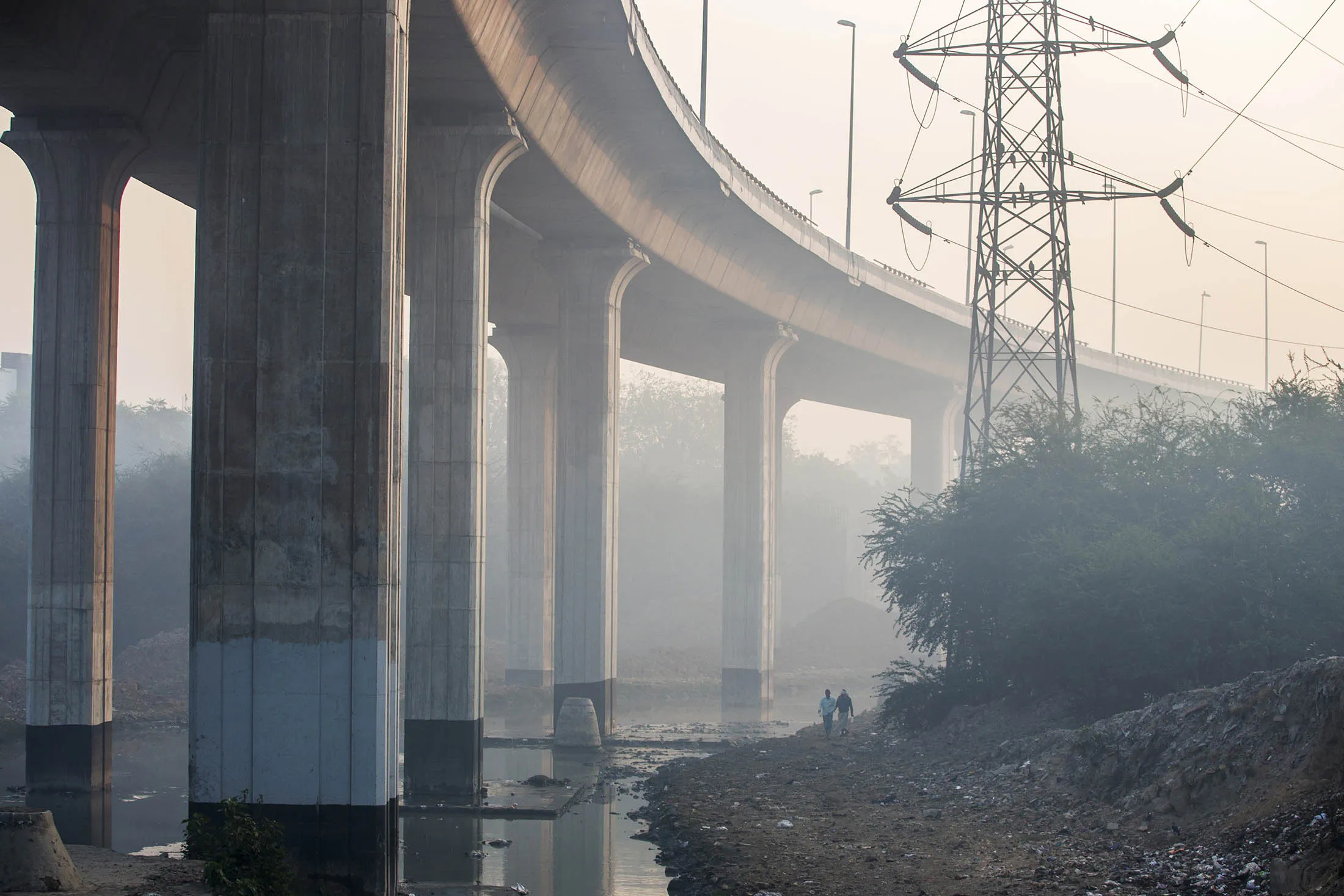 Pedestrians walk under an elevated highway shrouded in smog in New Delhi, India, on Monday, Jan. 11, 2016. A 2-judge Delhi High Court panel headed by Chief Justice G. Rohini allowed the odd-even traffic restrictions to continue. The measure by Delhi Chief Minister Arvind Kejriwal is the most concerted effort by the government yet to reduce the number of exhaust-belching automobiles in the world's most polluted metropolitan area as discontent among the city's 16.8 million residents grows.
