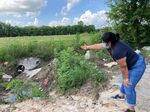 Shirley Ronquillo, a Houston area community activist, points to an open drainage ditch that is blocked by debris and trash May 27, 2021, in Houston. The ditch is located near a subdivision in an unincorporated part of Harris County that has a history of flooding. The U.S. Department of Housing and Urban Development says Texas' administration of flood relief money from Hurricane Harvey broke federal law by discriminating against Black and Hispanic residents of the Houston area. The federal agency's decision could channel millions of dollars of aid to communities battered by the 2017 storm. (AP Photo/Juan A. Lozano File)