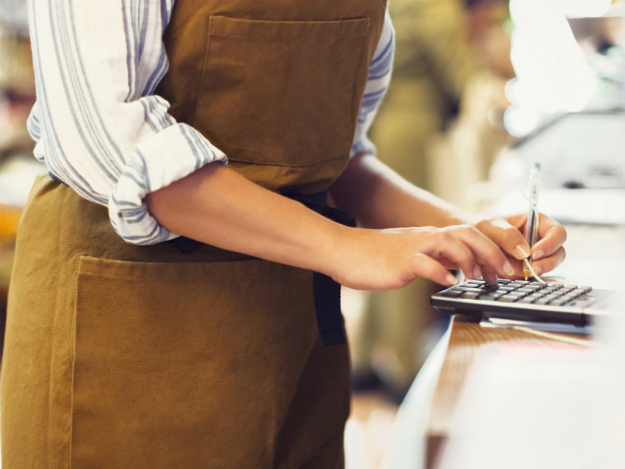 Female cashier using calculator in grocery store
