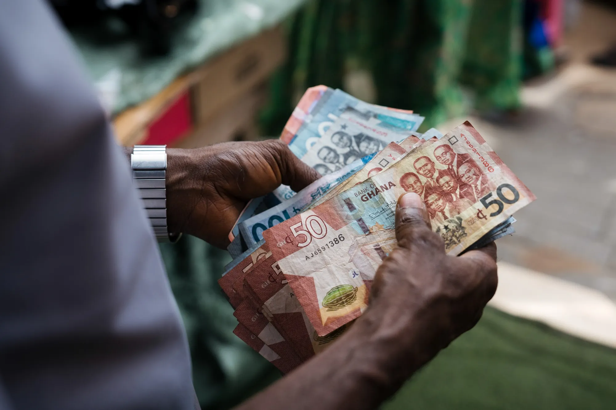 A street vendor counts Ghanaian cedi currency banknotes in a market in Accra, Ghana.