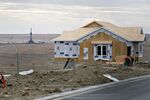 A crude oil drill rig in the distance of a single-family home under construction in Williston, North Dakota
